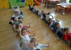 Dzieci siedzą w rzędach na podłodze